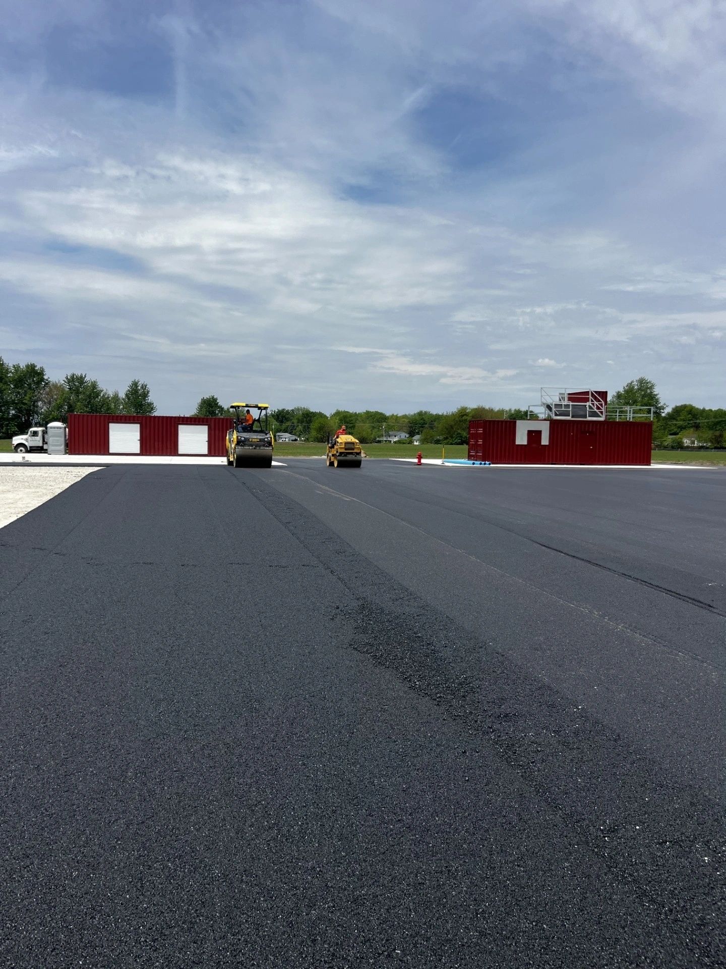 Two rollers compacting fresh asphalt on a heavy-use site
